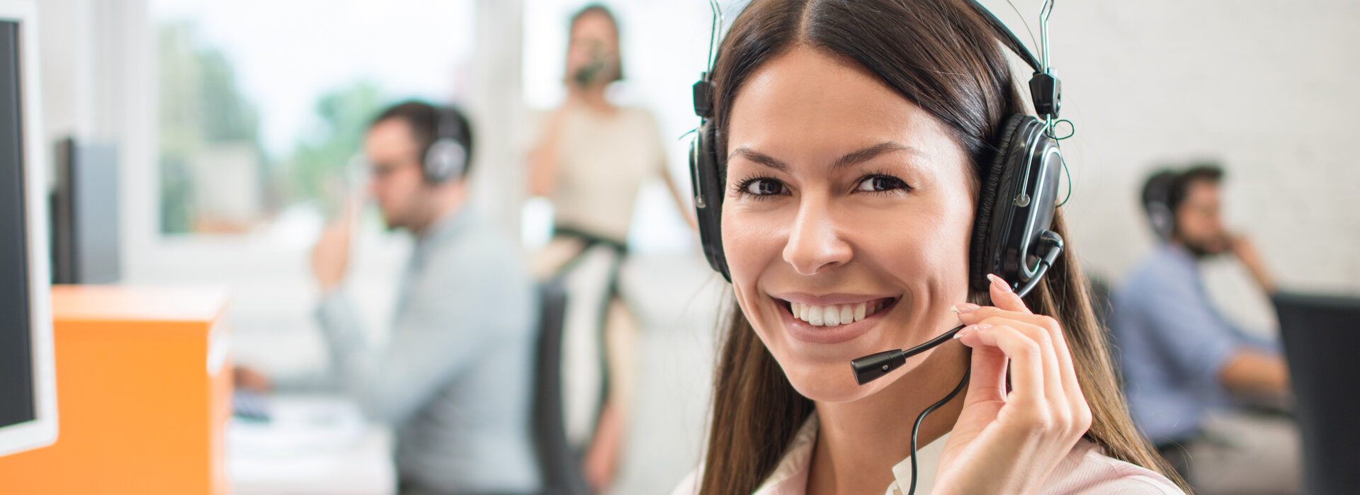 Eine Dame telefoniert mit Kopfhörer im Büro.